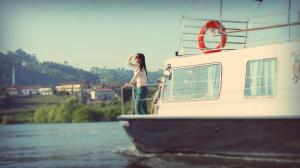 een vrouw die op de voorkant van een boot in het water staat bij Douro Houseboats in Marco de Canavezes