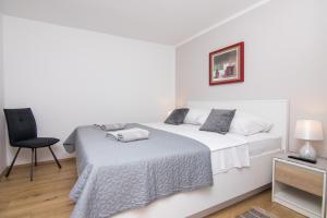 um quarto branco com uma cama e uma cadeira em Apartman Mara em Krk