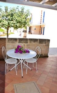 Favignana Casa Vacanza Orsola في فافينانا: طاولة بيضاء وكراسي مع الزهور على الفناء