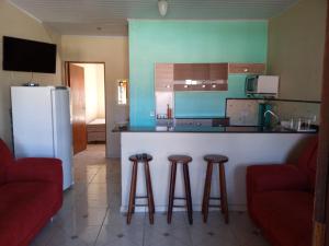 cocina con barra con taburetes y nevera en Residencial Chalés Lunamar Ubatuba, en Ubatuba