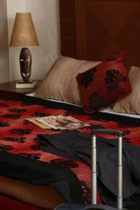 ein Schlafzimmer mit einem Bett und einem Tisch mit einer Lampe in der Unterkunft Hala Hotel & Aqua Park in Bissau
