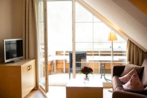 a living room with a couch and a television at Landhaus Bergkrone in Willingen
