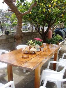 a wooden table with white chairs and an orange tree at Artemis Studios in Agia Roumeli