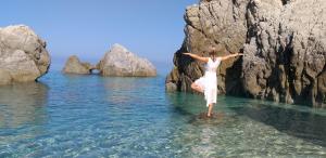 a woman standing in the water in front of rocks at Borgo di Santa Barbara in Santa Domenica