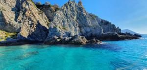a beach with blue water and a rocky cliff at Borgo di Santa Barbara in Santa Domenica