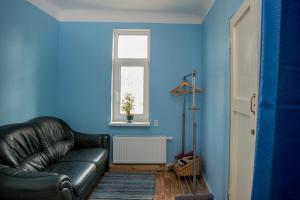 a black leather couch in a blue room with a window at Timemachine Apartment in Valmiera