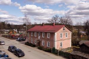 a large brick house with a red roof on a street at Timemachine Apartment in Valmiera