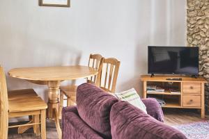 een woonkamer met een bank en een tafel met een tv bij Tree Pipit Cottage in Stockland