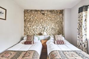 twee bedden in een kamer met een stenen muur bij Tree Pipit Cottage in Stockland