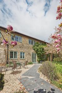 a stone house with chairs and a patio at Millthorn Cottage in Stockland