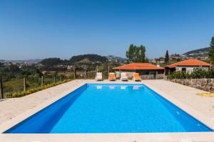 a blue swimming pool with two chairs and a house at Partezins III in Castelo de Paiva