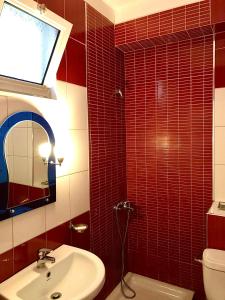 a red tiled bathroom with a sink and a toilet at Hotel NINO in Dhërmi +32 photos