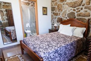 a bedroom with a bed and a stone wall at Partezins III in Castelo de Paiva