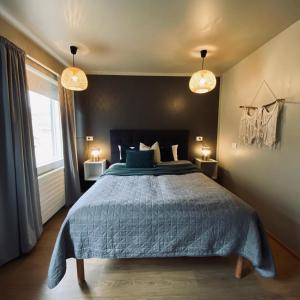 een slaapkamer met een bed met een blauw dekbed en 2 lampen bij Guesthouse Stekkaból in Patreksfjörður