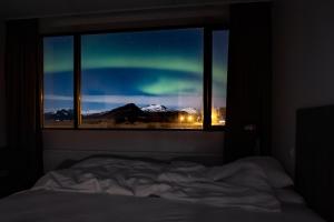 a bedroom with a window looking out at the northern lights at Milk Factory in Höfn