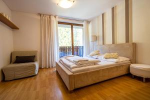 a bedroom with a bed and a chair and a window at Fatrapark 2 Apartments HRABOVO - Hlavná recepcia in Ružomberok