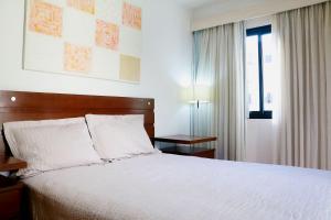 - une chambre avec un lit doté de draps blancs et une fenêtre dans l'établissement Rio Sunset Arpoador!, à Rio de Janeiro
