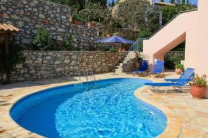 een zwembad met blauwe stoelen en een stenen muur bij Villa Mirella in Tselendáta