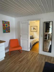 a living room with an orange chair and a bedroom at Lillhuset Norr Sälens By in Sälen