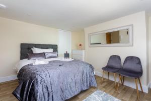 a bedroom with a bed and two purple chairs at St Mary's - Modern Central Huge Studio Apartments in Southampton +7 photos