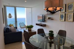 a living room with a glass dining room table with chairs at Camino al Mar. Exclusivo depa con vista al mar in Mazatlán