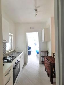 a white kitchen with a stove top oven next to a door at Emidio House in Termini