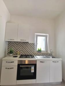 a white kitchen with a stove and a sink at Emidio House in Termini