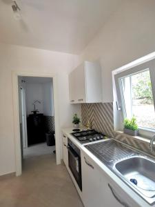 a kitchen with a stove and a sink and a window at Emidio House in Termini