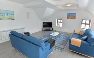sala de estar con 2 sofás azules y TV en Pier House Luxury Apartment en Dingle