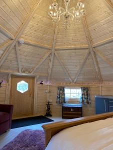 um quarto amplo com uma cama e um lustre em Woodland Lodge Oxen Craig em Kintore