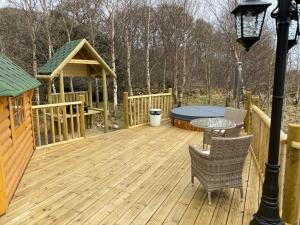 a wooden deck with a gazebo and a table and chairs at Woodland Lodge Oxen Craig in Kintore