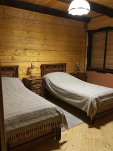 two beds in a room with wooden walls at Карпатский Рай in Yaremche