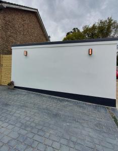 Una puerta de garaje blanca con dos luces. en Cosy detached studio- walking distance to CWOA!, en Chessington