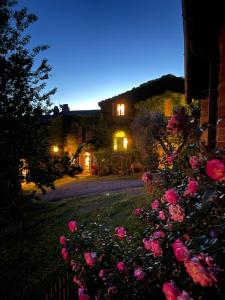 uma casa com rosas rosas no quintal à noite em Pieve di Caminino Historic Farm em Podere Caminino