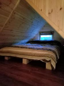 uma cama no sótão de uma casa de madeira em Gajóweczka em Jałowo