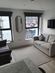 uma sala de estar com um sofá e duas janelas em Coastal Links em Portrush