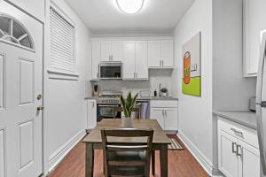 a kitchen with white cabinets and a wooden table and chairs at 2BR Apartment in Great Spot with Fast Wi-Fi - Roscoe 30 in Chicago