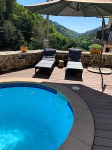 a swimming pool with two lounge chairs and an umbrella at O Remanso Dos Patos in Penalba