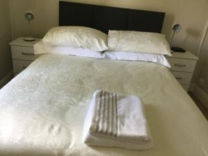 a white bed with white towels and pillows on it at Adare Luxury Riverside Apartment in Limerick