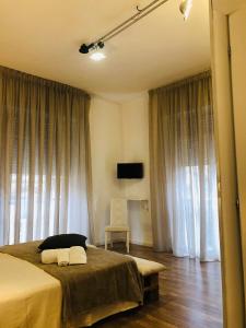 1 dormitorio con cama, silla y cortinas en B&B Degli Artisti en Lecce