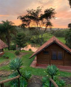 uma pequena casa num campo com um lago em Pousada Gota de Minas em Santo Antônio do Leite