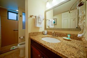 a bathroom with a sink and a mirror and a toilet at La Costa Beach Club by Capital Vacations in Pompano Beach
