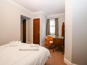 a bedroom with a bed and a desk and a table at Courtyard Cottage in Letham