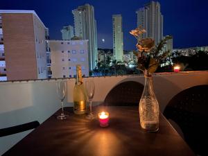 einen Tisch mit zwei Flaschen, zwei Gläsern und einer Kerze in der Unterkunft Apartamentos JS Playa in Finestrat