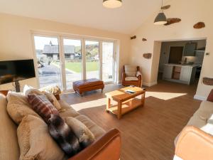 ein Wohnzimmer mit einem Sofa und einem Tisch in der Unterkunft The Cottage in Pwllheli