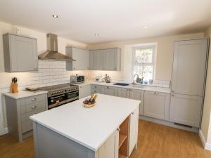 a kitchen with white cabinets and a white counter top at The Cottage in Pwllheli
