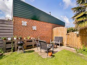 a patio with chairs and a grill in a backyard at Lovely Bungalow in Noordwijkerhout with Garden in Noordwijkerhout