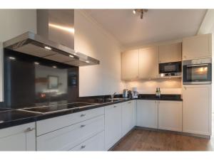een keuken met witte kasten en zwarte aanrechtbladen bij Holiday home with whirlpool quiet area in Zeeland in Colijnsplaat