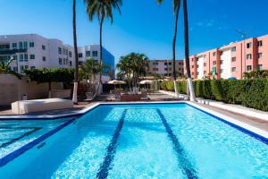 a swimming pool with palm trees and buildings at Suites Santa Barbara in Manzanillo