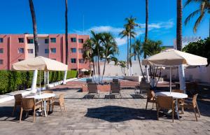um pátio com mesas, cadeiras e guarda-sóis em Suites Santa Barbara em Manzanillo